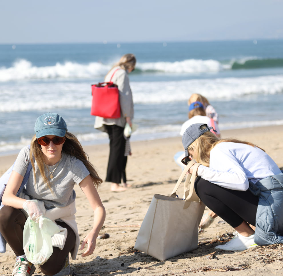 Shot of people at a beach cleaning up trash.