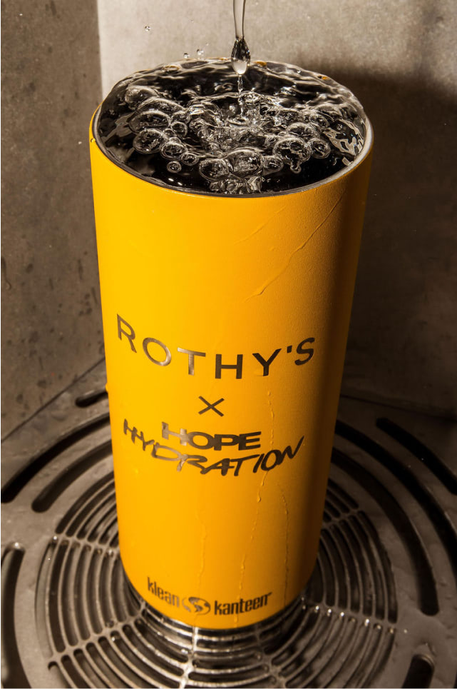 Yellow Rothy's x Hope Hydration cup with water being poured into it on a metallic surface.