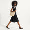 Alternate view of the Mini Zip Bucket in Knot Brown worn as a crossbody by a female model, shown in motion from the right.