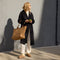 An alternate view of a model holding The Zip Travel Tote in Hazelnut.