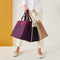 Model holding The Classic Tote in multiple colors.