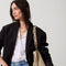 An alternate image of The Braided Shoulder Strap in Cream & Cocoa, shown paired with The Bucket Bag and held by a model. 