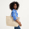hover | Model holding The Zip Travel Tote in Parchment Basketweave.