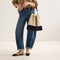 Alternate view of a model wearing The Cinch Bucket Bag in Black and White Raffia-Knit shown from the front.