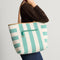 Alternate view of a model carrying The Two Way Tote in Ivy, showing the striped side.