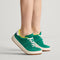 hover | A child modeling The Kids Stretch Sneaker in Emerald Pop.