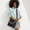 hover | Overlay:: Shown with The Shoulder Strap (sold separately.) | Alt:: The Mini Zip Bucket in Black Sand, carried over the shoulder of a female model, shown from the front.
